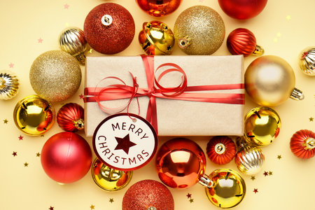 Gift box with Christmas balls and stars on beige background