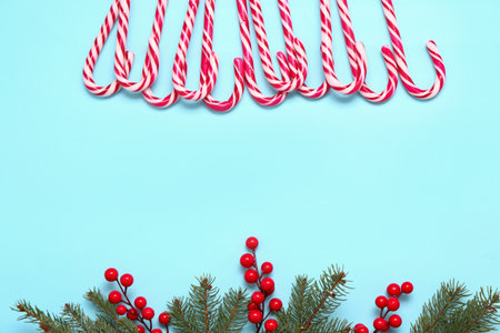 Composition with sweet candy canes, fir branches and cranberry on color backgroundの写真素材