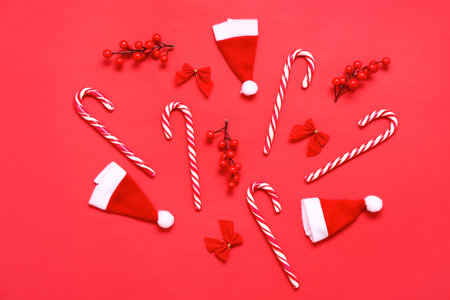 Composition with candy canes, Santa hats and Christmas decor on red backgroundの写真素材