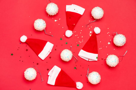 Composition with Santa hats, Christmas balls and sequins on red backgroundの写真素材