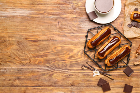 Grid with tasty eclairs, cup of coffee and chocolate on wooden background