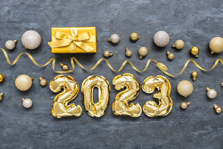 Figure 2023 made of balloons, Christmas balls, serpentine and gift on dark backgroundの写真素材