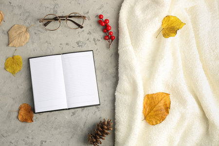 Composition with blank notebook, eyeglasses, autumn leaves and warm plaid on grunge backgroundの写真素材