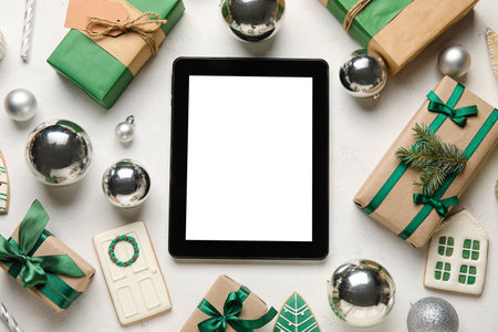 Blank tablet computer with Christmas balls, cookies and gifts on white backgroundの写真素材