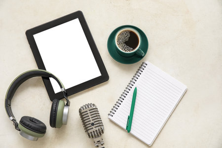 Notebook with tablet computer, headphones, microphone and coffee cup on white background. Podcast conceptの写真素材
