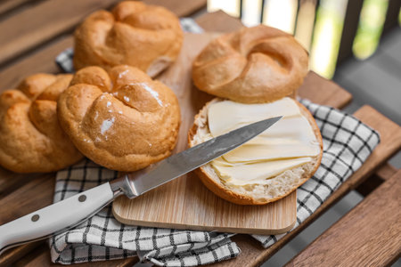 Kaiser rolls with butter on wooden board