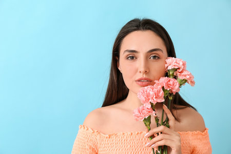 Young woman with beautiful carnation flowers on color backgroundの写真素材