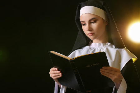 Young nun with Bible on dark backgroundの写真素材