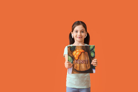 Little girl with earphones and book on color backgroundの写真素材