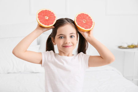 Little girl with fresh tasty grapefruit in the bedroomの写真素材