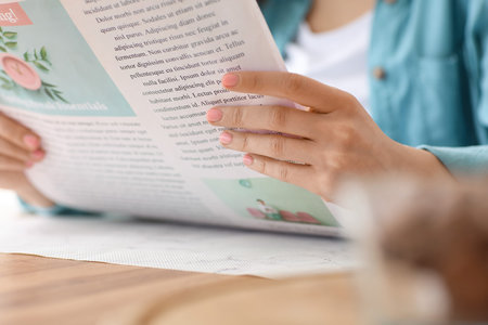 Young woman reading newspaper at home, closeupの写真素材