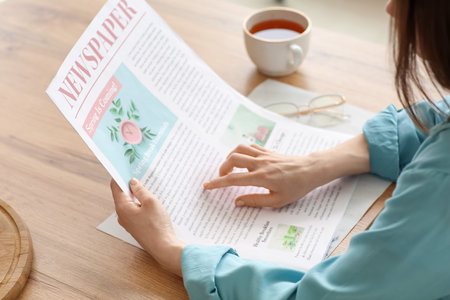 Young woman reading newspaper at home, closeupの写真素材