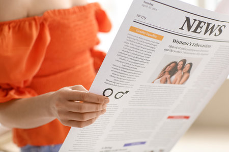 Young woman reading newspaper at home, closeupの写真素材