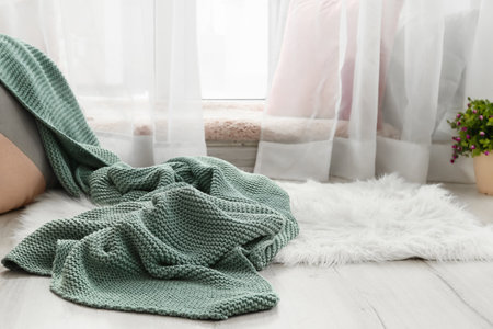 Cozy place for rest with pillows and knitted plaid near window