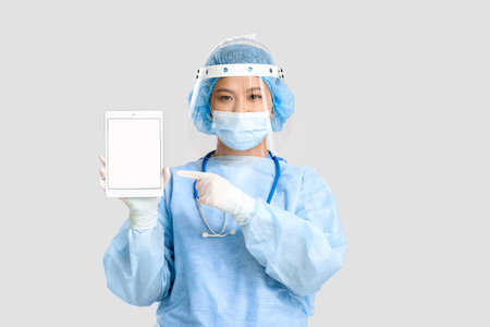 Portrait of female Asian surgeon with tablet on light backgroundの写真素材