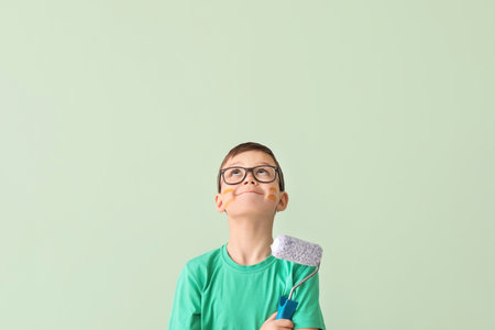 Cute little boy with paint roller near color wallの写真素材