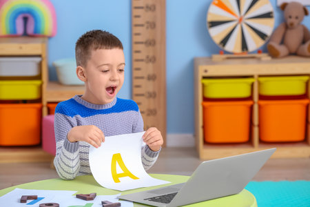 Little boy with laptop training pronounce letter A at homeの写真素材