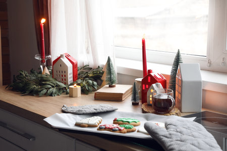 Candle holders with Christmas decor, cup of tea and cookies on counter in kitchenの写真素材
