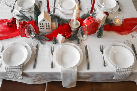 Christmas table setting with candle holders and fir branches in dining roomの写真素材