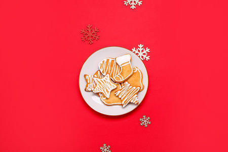 Plate with tasty Christmas cookies and decorations on red background