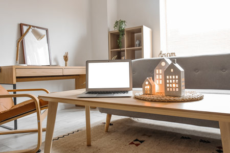 House shaped candle holders and laptop on table in living roomの写真素材