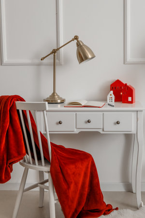 House shaped candle holders, notebook and lamp on table near light wallの写真素材