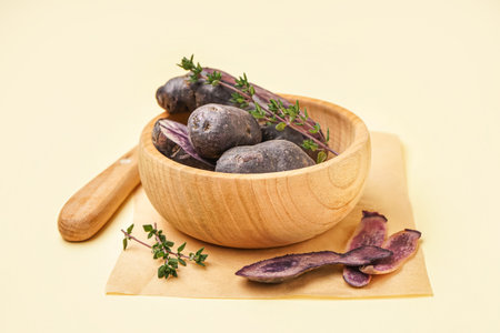 Wooden bowl with raw purple potatoes and thyme on color backgroundの写真素材