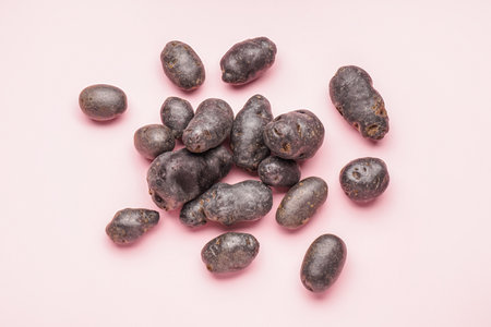 Raw purple potatoes on pink background