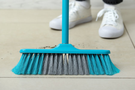 Woman sweeping light tile floor with broom, closeupの写真素材