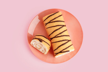 Plate with sweet sponge cake roll on pink backgroundの写真素材