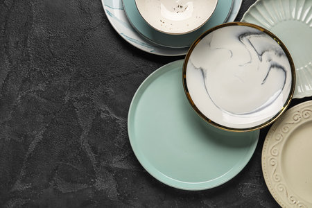 Different empty plates on black grunge background