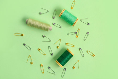 Thread spools and safety pins on green backgroundの写真素材