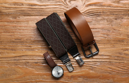 Male wristwatch, suspenders and leather belt on wooden backgroundの写真素材