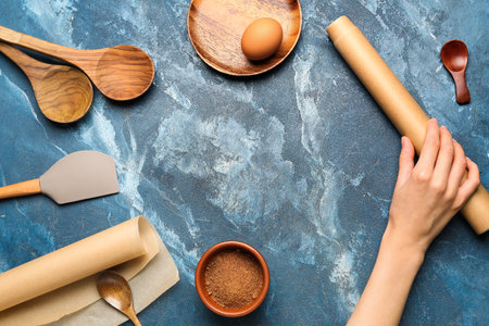 Frame made of kitchen utensils and female hand with baking paper on blue backgroundの写真素材