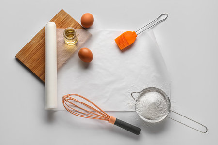 Baking paper with kitchen supplies and ingredients on white backgroundの写真素材