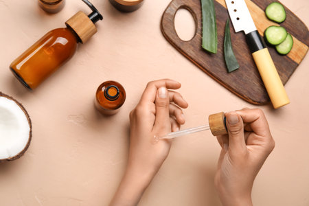 Young woman applying essential oil onto hand on color backgroundの写真素材