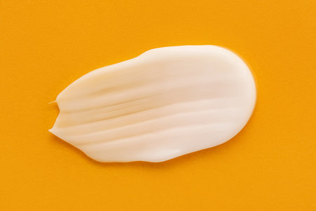 Smear of moisturizing cream on yellow backgroundの写真素材