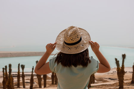 Little girl with wicker hat in desert, back viewの写真素材