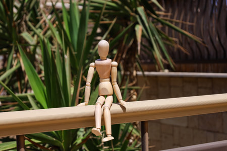 Wooden mannequin on railing in park, closeup