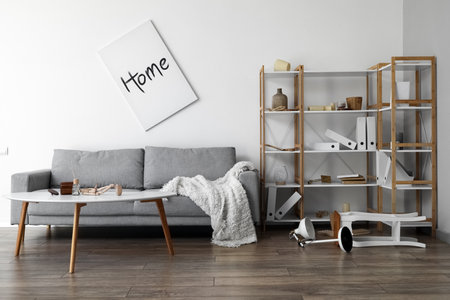 Interior of messy living room with gray sofa, tables and shelving unitの写真素材