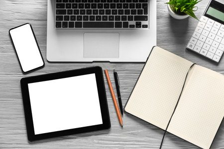Mobile phone with laptop, tablet computer and notebook on gray wooden background. trading concept