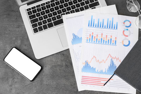 Mobile phone with laptop and charts on dark background. trading conceptの写真素材