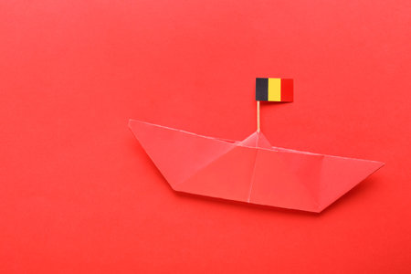 Paper ship and small flag of Belgium on red backgroundの写真素材
