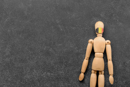 Wooden mannequin doll and small Belgian flag on dark backgroundの写真素材