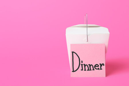 Box with Asian food and sticky note with word DINNER on color backgroundの写真素材