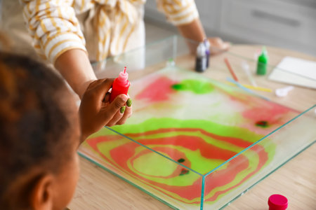 Little girl and teacher with paints in workshop for Ebru painting, closeupの写真素材
