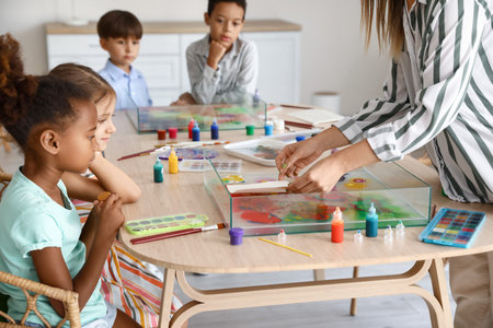 Teacher with little children marbling paper during master class in Ebru
