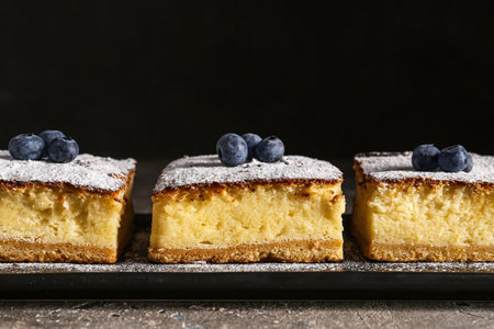 Pieces of cheese pie with blueberries on slate board against black backgroundの写真素材