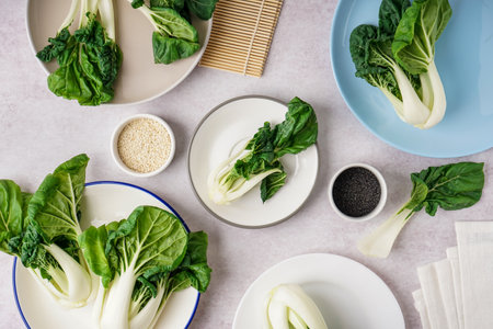 Plates of fresh pak choi cabbage and sesame seeds on light backgroundの写真素材