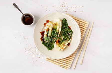 Plate of tasty stewed pak choi cabbage and soy sauce on light backgroundの写真素材